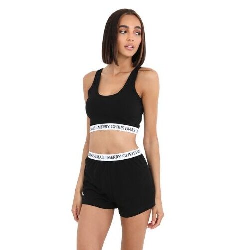 A woman wearing a crop top and shorts pyjama set with the slogan Merry Christmas printed on it